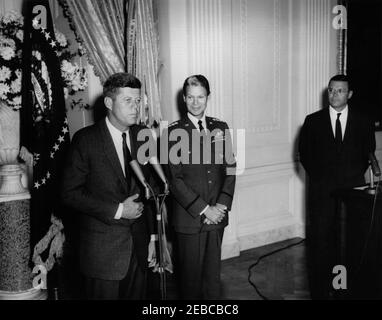 Presentation of the Distinguished Service Medal (DSM) to Gen. Lauris Norstad, 12:45PM. President John F. Kennedy (left, at microphones) delivers remarks during the presentation of the Distinguished Service Medal to retired Supreme Allied Commander of NATO, General Lauris Norstad. General Norstad stands right of President Kennedy; Secretary of Defense, Robert S. McNamara, stands at right, behind lectern. East Room, White House, Washington, D.C. Stock Photo