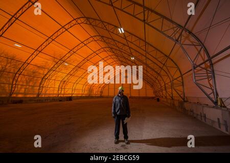 Construction working standing in the middle of an empty temporary warehouse tent, Pennsylvania, USA Stock Photo