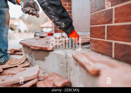 Laying curly tiles on glue - imitation of natural stone - facing the house from the outside Stock Photo