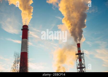 Toxic smoke from factory chimneys into a clear sky - oxygen pollution by combustion products Stock Photo