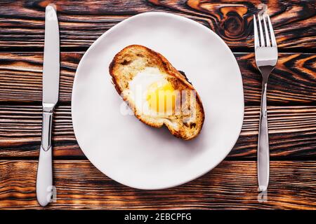 Fried eggs in a piece of white bread toasted on a plate - delicious hearty rustic breakfast made from natural products Stock Photo