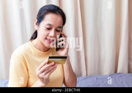 Happy asian women use smart phone and creadit card speak to pay shopping online. Women use smartphone order shopping online and pay with creadit card. Stock Photo