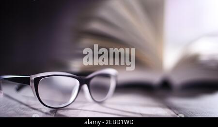 Composition with glasses and open book on the table. Stock Photo
