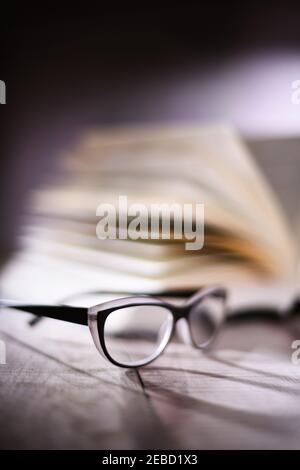 Composition with glasses and open book on the table. Stock Photo