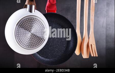 Two hanging frying pans and kitchen utensils Stock Photo