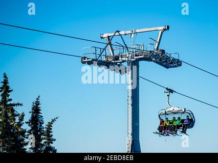 Group of skiers riding a ski lift to the top of a mountain at a ski resort. Stock Photo