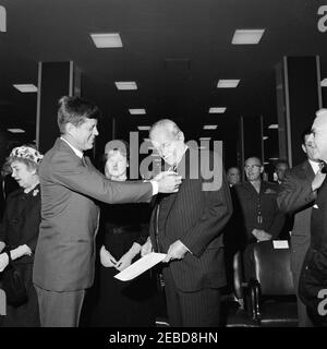 Presentation of the National Security Medal to Allen Dulles, 11:00AM. President John F. Kennedy pins the National Security Medal on the lapel of Allen W. Dulles, retiring director of the Central Intelligence Agency (CIA). Director of the Federal Bureau of Investigation (FBI) J. Edgar Hoover (to the right of Mr. Dulles) and Commandant of the United States Marine Corps General David M. Shoup (wearing glasses; to the right of Director Hoover) are in the background. CIA headquarters, Langley, Virginia. Stock Photo