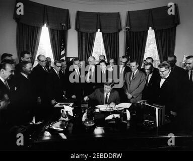 Bill signing - S. 2965 Public Law 87658, Accelerated Public Works Program, 9:30AM. President John F. Kennedy (seated at desk) signs S. 2965, the Public Works Acceleration Act. Looking on (L-R): unidentified stenographer (seated, partially hidden on edge of frame); Secretary of the Department of Health, Education, and Welfare (HEW), Anthony J. Celebrezze; Senator Stephen M. Young (Ohio); Senator Edmund S. Muskie (Maine); Senator Pat McNamara (Michigan); Senator John Sherman Cooper of Kentucky (in back); Senator Dennis Chu00e1vez (New Mexico); Senator Jennings Randolph (West Virginia); Represen Stock Photo