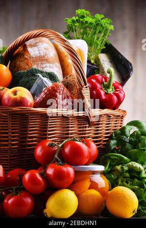 Wicker basket with assorted grocery products including fresh vegetables and fruits Stock Photo