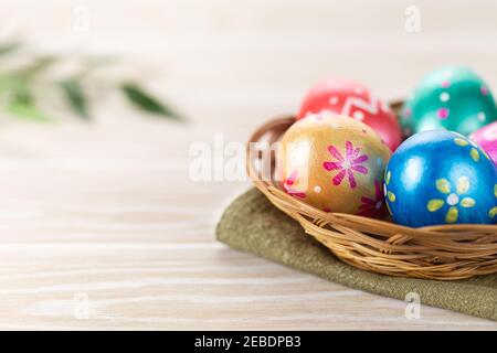 Five easter eggs trendy colored deep blue, green, orange, magenta and golden decorated in basket on white background. Copy space for text. Stock Photo