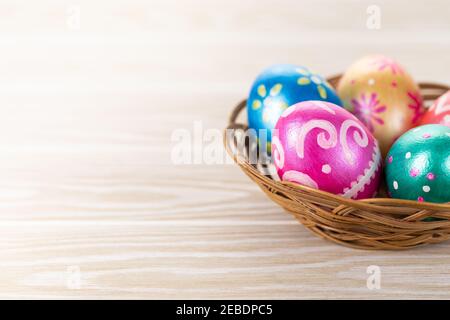 Five easter eggs trendy colored deep blue, green, orange, magenta and golden decorated in basket on white background. Copy space for text. Stock Photo