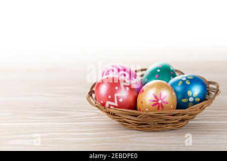 Five easter eggs trendy colored deep blue, green, orange, magenta and golden decorated in basket on white background. Copy space for text. Stock Photo