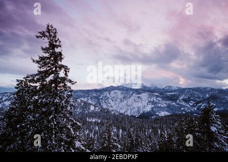 Sunset over snow covered mountains with blue and purple hues Stock Photo