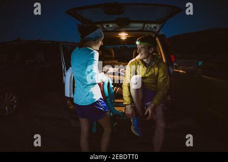 Man and Woman sit and laugh after a long trail run in the mountains Stock Photo