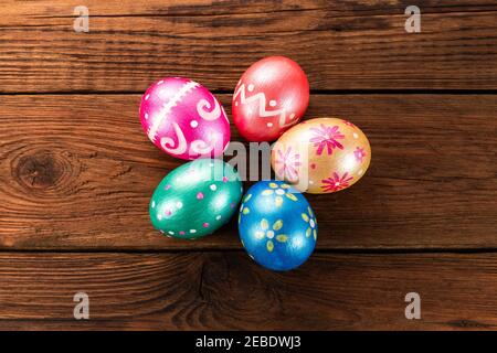 Five easter eggs trendy colored classic blue, green, orange, magenta and golden decorated on old wooden table. Copy Space. Stock Photo