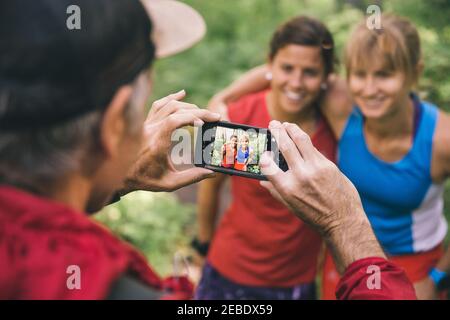 Three friends running together stop to take a picture on smart phone Stock Photo