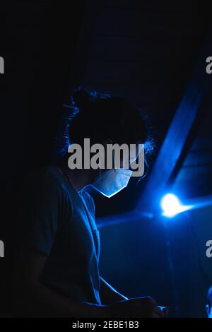 Young man working with a protection mask and blue ligth behind Stock Photo
