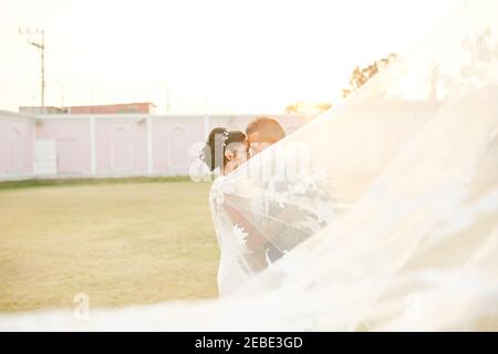 newly married couple looking at each other while the bride's veil pass Stock Photo