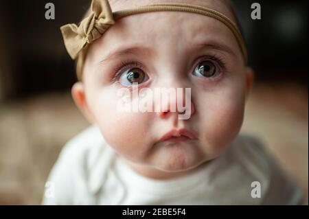 Close up of sad baby girl with pouting lips and big tearful eyes Stock Photo