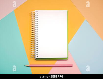 workspace desk with spiral notepad and pink pen with copy space background on colorful background Stock Photo