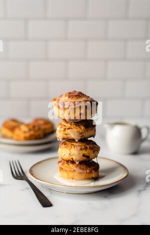 Stack of fresh cinnamon buns on plate with white tile background. Stock Photo