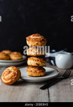Stack of freshly baked cinnamon buns on plate with black background. Stock Photo
