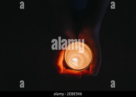 Above view of hands holding lit candle Stock Photo