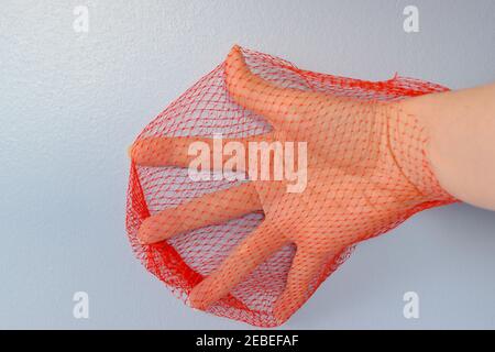 Female hand in red net, symbol of restricted movement, pain, virus spread. Stock Photo