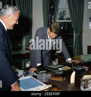 Presentation to President Kennedy of a John Adams letter to President Madison, 12:55PM. President John F. Kennedy leans over his desk to view an original letter written by former President John Adams to President James Madison, presented to President Kennedy by Alphonsus J. Donahue, Jr. (left). Oval Office, White House, Washington, D.C. Stock Photo