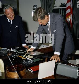 Presentation to President Kennedy of a John Adams letter to President Madison, 12:55PM. President John F. Kennedy leans over his desk to view an original letter written by former President John Adams to President James Madison, presented to President Kennedy by Alphonsus J. Donahue, Jr. (left). Oval Office, White House, Washington, D.C. Stock Photo