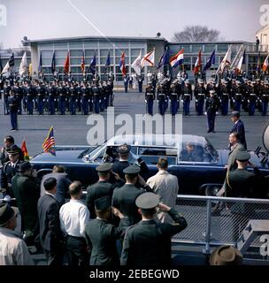 Arrival ceremony for Sylvanus Olympio, President of Togo, 11:00AM. President John F. Kennedy and President Sylvanus Olympio of Togo sit in the back seat of a bubbletop limousine, following arrival ceremonies for President Olympio. White House Secret Service agents, Roy Kellerman (at right, wearing hat) and Sam Sulliman (far left), walk alongside car. Military troops stand at attention in background. Military Air Transport Service (MATS) Terminal, Washington National Airport, Washington, D.C. Stock Photo