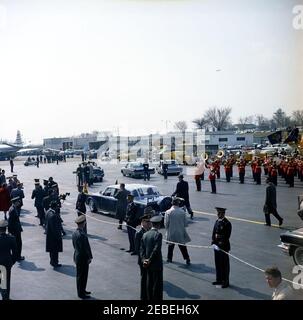 Arrival ceremony for Sylvanus Olympio, President of Togo, 11:00AM. A bubbletop limousine, carrying President John F. Kennedy and President Sylvanus Olympio of Togo, drives through the Military Air Transport Service (MATS) Terminal at Washington National Airport, following arrival ceremonies for President Olympio. Also pictured are White House Secret Service agents Sam Sulliman, Roy Kellerman, and Bob Lilley. US Marine Band plays in background. Washington, D.C. Stock Photo