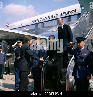 Arrival ceremony for Sylvanus Olympio, President of Togo, 11:00AM. President John F. Kennedy (left) shakes hands with President of Togo, Sylvanus Olympio, upon President Olympiou2019s arrival in Washington, D.C. US Chief of Protocol, Angier Biddle Duke, walks down airplane stairs behind President Olympio. White House Secret Service agent, Roy Kellerman, stands at left in background. All others are unidentified. Military Air Transport Service (MATS) Terminal, Washington National Airport, Washington, D.C. Stock Photo