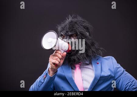 businessman wearing gorilla mask and screaming to megafon Stock Photo