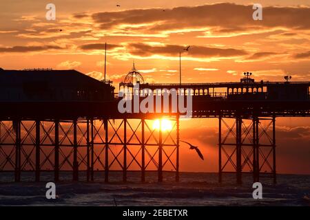 Brighton UK 12th February 2021 - The sun sets behind Brighton Palace Pier after a beautiful sunny but cold day on the south coast : Credit Simon Dack / Alamy Live News Stock Photo