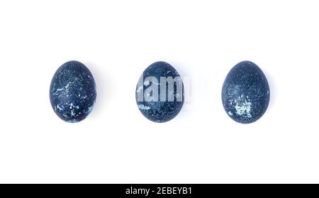 The three eggs are colored with natural dyes with a dark blue color on a white background. Stock Photo