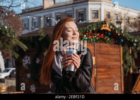Slow living in city environment, Urban Slow life, mindfulness, enjoying the moment, work-life balance. Young redhead woman enjoying the sun and Stock Photo