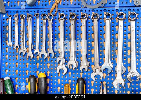 A range of used mechanic tools, from combination wrenches to screwdrivers. All hanging on blue panels. Perfect shot for arts and crafts. Stock Photo