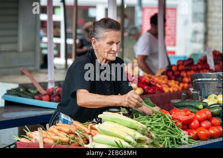 Split - Croatia - August 25, 2019: Elderly woman sells vegetables at a market in Split, Croatia Stock Photo