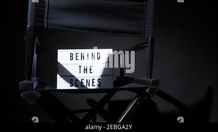 Behind the scenes letterboard text on Lightbox or Cinema Light box. Movie clapperboard and director chair. Background black color. camera shootin in v Stock Photo