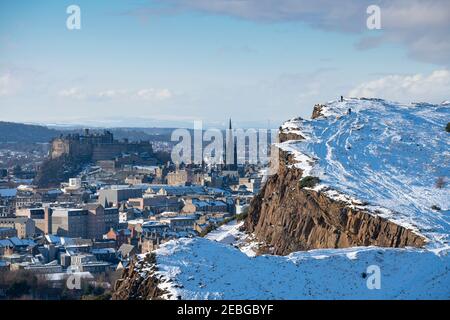 View of Salisbury Crags covered in snow in winter in Holyrood Park with Edinburgh Castle to rear, Edinburgh, Scotland, UK Stock Photo