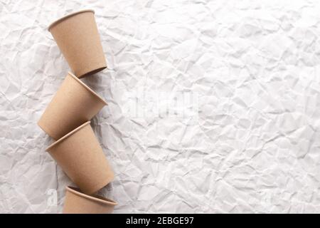disposable kraft paper cups laid out on gray crumpled paper in geometric pattern Stock Photo