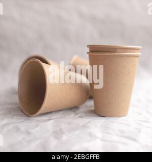 disposable kraft paper cups laid out on gray crumpled paper in geometric pattern Stock Photo