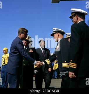 Visit to the Atlantic Fleet: President Kennedy views fleet demonstration aboard USS Enterprise. President John F. Kennedy (left, wearing sunglasses) shakes hands with an unidentified United States Navy rear admiral on the flight deck of the aircraft carrier USS Enterprise, at sea off the coast of North Carolina. Admiral Robert L. Dennison, Commander in Chief of the Atlantic Command (CINCLANT), Commander in Chief of the U.S. Atlantic Fleet, and Supreme Allied Commander, Atlantic (SACLANT), stands right of President Kennedy; Secretary of Defense Robert S. McNamara (center) stands in the backgrou