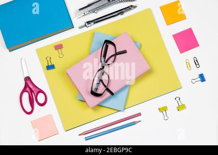 Pastel color books, pencils, paper clips, glasses and colorful paper on white isolated background. Education concept with blank book cover with copy s Stock Photo