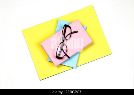 Pastel pink and blue books with glasses and yellow paper on white isolated background. Education concept with blank book cover with copy space for tex Stock Photo
