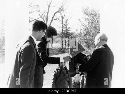 Meeting with the Prime Minister of Italy Amintore Fanfani, 10:00AM. Prime Minister of Italy, Amintore Fanfani (right), presents Caroline Kennedy with a gift of a doll; President John F. Kennedy looks on. State Department interpreter, Neil Seidenman, stands at far left. West Wing Colonnade, White House, Washington, D.C. Stock Photo