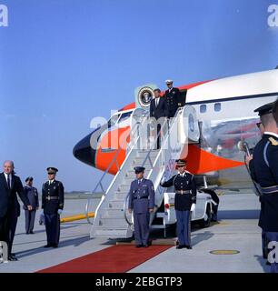 President Kennedy returns to Andrews Air Force Base from Easter vacation, 4:33PM. President John F. Kennedy (holding hat) exits Air Force One upon his arrival at Andrews Air Force Base, Maryland, following Easter vacation in Palm Beach, Florida. Also pictured: Naval Aide to the President, Captain Tazewell T. Shepard, Jr. (at top of airplane stairs, behind President Kennedy), and Secretary of State, Dean Rusk (bottom left, on edge of frame).
