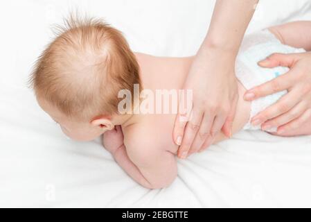 Three month baby boy receiving back massage from a female massage therapist. Relaxing newborn kid. Close up. The masseur gives the child a back massag Stock Photo