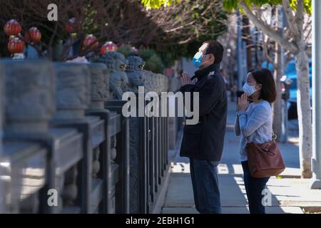 Los Angeles, California, USA. 12th Feb, 2021. People wearing face masks pray outside the closed Thien Hau Temple on the first day of the Chinese Lunar New Year, the Year of the Ox on the Chinese zodiac, during the Coronavirus Pandemic. Credit: Ringo Chiu/ZUMA Wire/Alamy Live News Stock Photo